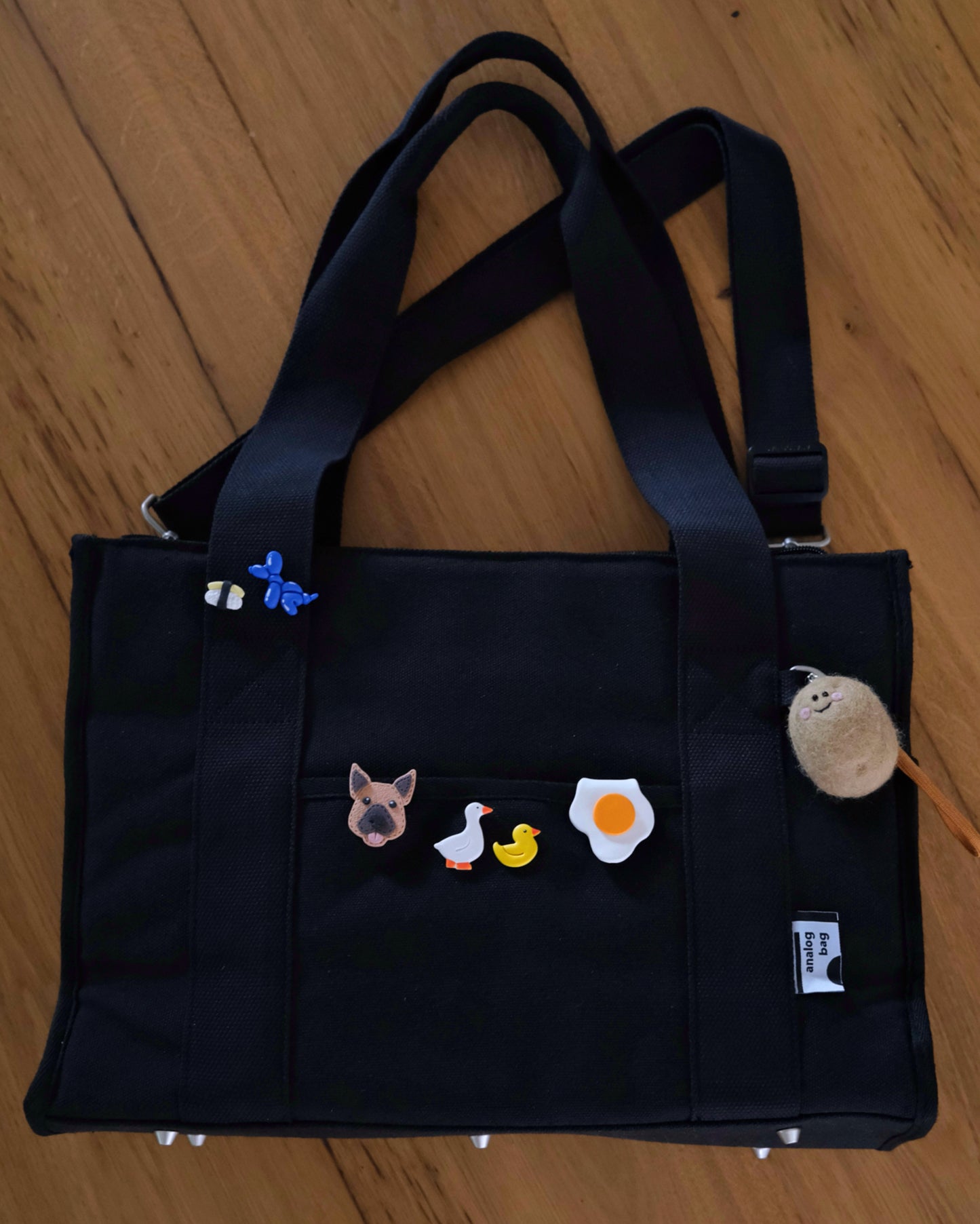 Black bag with various appliqués on a wooden surface